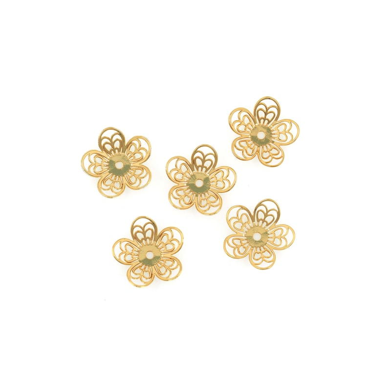 May include: Five gold-colored metal flower-shaped bead caps with a hole in the center.