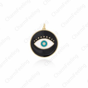 K&ouml;nnte beinhalten: Ein goldfarbener Anh&auml;nger mit einem schwarzen Emaille-Kreis, einem wei&szlig;en Auge und einer blauen Pupille. Das Auge hat einen kleinen Diamanten in der Mitte.