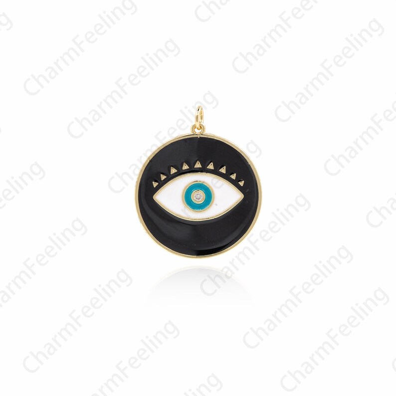 K&ouml;nnte beinhalten: Ein goldfarbener Anh&auml;nger mit einem schwarzen Emaille-Kreis, einem wei&szlig;en Auge und einer blauen Pupille. Das Auge hat einen kleinen Diamanten in der Mitte.