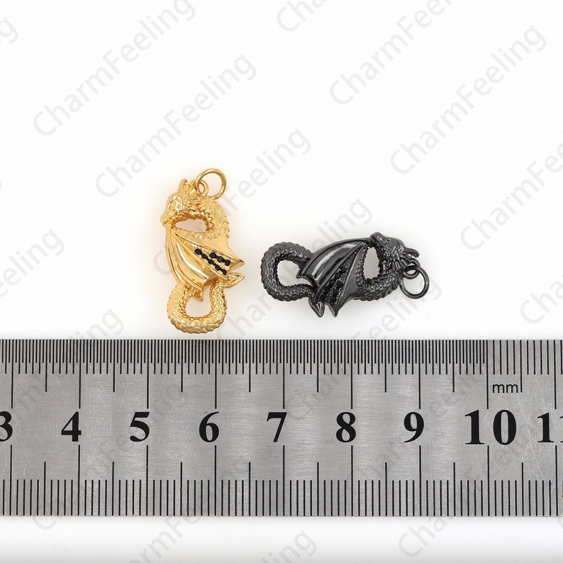 May include: Two dragon-shaped clasps, one gold and one black, are shown against a white background. A ruler is placed below the clasps, showing that each clasp is approximately 2.5 cm long.