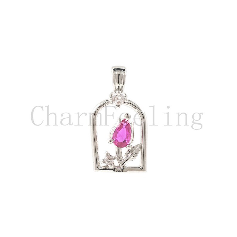 May include: Silver pendant featuring a pink rose with a pear-shaped gemstone in the centre, surrounded by smaller clear gemstones. The rose is enclosed in a silver frame.