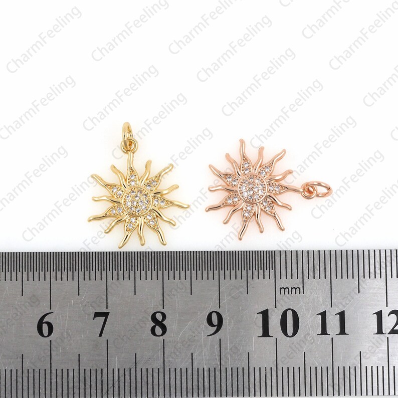 Puede incluir: Dos colgantes de sol de tono dorado con detalles de cristal transparente. Los colgantes miden aproximadamente 2,5 cm de di&aacute;metro y se miden con una regla.