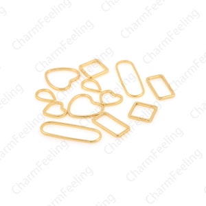May include: A collection of gold-toned metal jump rings in various shapes, including circles, ovals, squares, rectangles, and hearts.