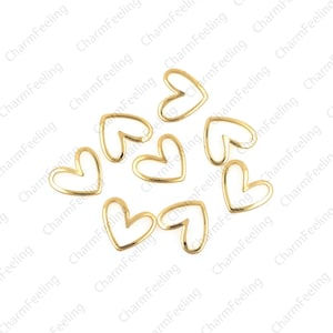 May include: A group of eight gold-colored metal heart-shaped charms. The charms are open on one side and have a smooth, polished finish.