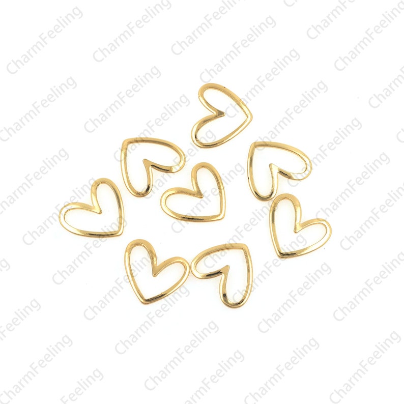 May include: A group of eight gold-colored metal heart-shaped charms. The charms are open on one side and have a smooth, polished finish.
