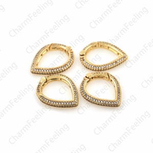 May include: Four gold-toned teardrop-shaped clasps with clear crystal embellishments. Each clasp has a hinged opening.
