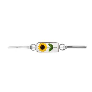 May include: A silver bracelet with a rectangular charm featuring a pressed sunflower.