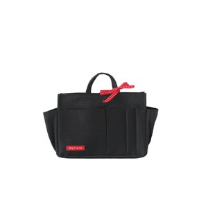 Puede incluir: Bolso tote de lona negra con múltiples bolsillos y una cinta roja con lunares blancos. El bolso tiene una etiqueta que dice "Myllora".