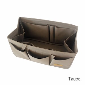 Puede incluir: Un organizador de tela color topo con múltiples compartimentos y bolsillos. El organizador está diseñado para caber dentro de un bolso de mano o una bolsa de compras. El organizador tiene una pequeña etiqueta que dice "Mylife".