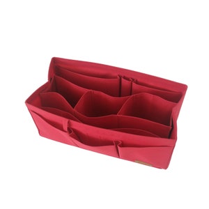 May include: Red felt bag organiser with multiple compartments and pockets. The organiser is designed to fit inside a larger bag and help keep it organised.