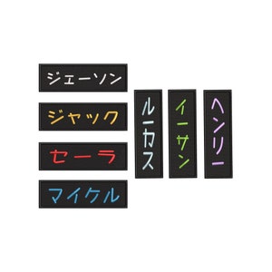 May include: Six black rectangular patches with Japanese text in various colours. The text reads "ジェーソン", "ジャック", "セラ", "マイケル", "ルカ", "イアン", and "ヘレン".