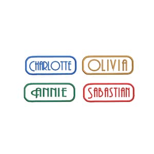 May include: Four rectangular name tags with rounded corners. The tags are in blue, gold, green, and red. The names on the tags are Charlotte, Olivia, Annie, and Sebastian.