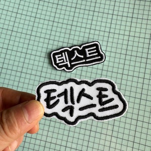 May include: Two white embroidered patches with black outlines. The first patch is rectangular and says "테스트" in black lettering. The second patch is a white cloud shape and says "테스트" in black lettering.