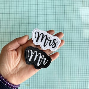 May include: Two iron-on patches, one black and one white, with the words "Mr" and "Mrs" in white and black embroidery, respectively.