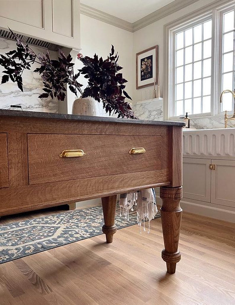 Close-up of solid brass end rails on the Kismet House Dairy Table handmade white oak kitchen island