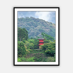 May include: A red pagoda with a green roof sits on a hillside covered in lush green trees. The pagoda is surrounded by trees and a stone wall. The sky is cloudy and blue.