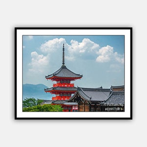 May include: A red and black pagoda with a blue sky and white clouds in the background. The pagoda has a pointed roof and multiple tiers. The image is taken from a low angle, looking up at the pagoda.