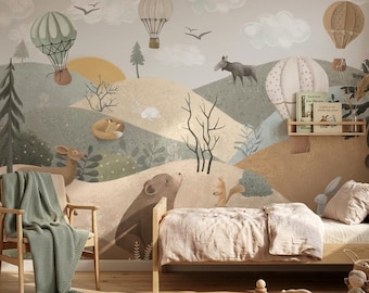 May include: A wall mural featuring a landscape with hot air balloons, clouds, birds, and forest animals including a bear, deer, and squirrel. A wooden bed with beige bedding, a wooden chair with a green throw, and a woven basket with toys are present.