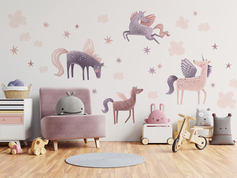 May include: A whimsical children's room featuring unicorn wall decals in shades of purple and pink, along with star and cloud accents. The room includes a pink chair, a white cabinet, and wooden toys, creating a playful and imaginative space.
