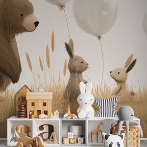 May include: A white storage unit with cubbies containing wooden toys, a white rabbit lamp, a striped cushion, a panda cushion, and a grey octopus plush. The wall features a mural of a brown bear, two rabbits, and balloons in a field.