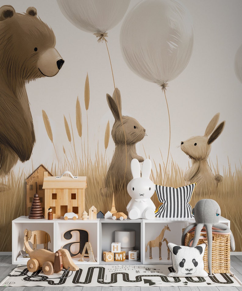 May include: A white storage unit with cubbies containing wooden toys, a white rabbit lamp, a striped cushion, a panda cushion, and a grey octopus plush. The wall features a mural of a brown bear, two rabbits, and balloons in a field.