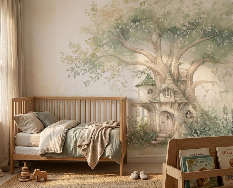May include: A wooden crib with a light green blanket and pillow sits against a wall featuring a large watercolor mural of a treehouse. The mural depicts a sprawling tree with green leaves and a small house built into its trunk with a wooden door.