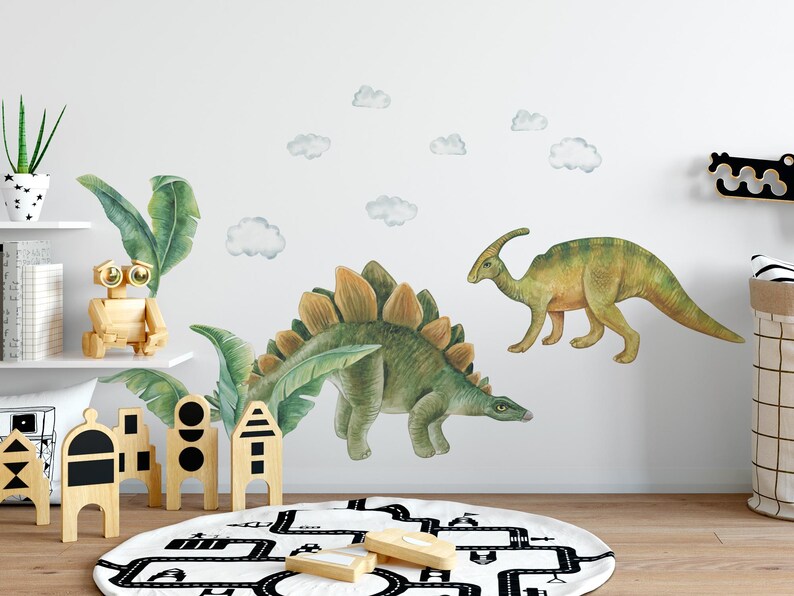 May include: Watercolor dinosaur wall decals in green and yellow, including a Stegosaurus and a Parasaurolophus. The decals are applied to a white wall with cloud accents. A wooden robot and other wooden toys are on a shelf.