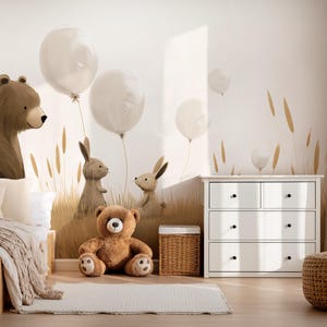 May include: A wall mural featuring a large brown bear, two rabbits, and white balloons in a grassy field. The scene includes a wooden bed with beige bedding, a brown teddy bear on the floor, a wicker basket, and a white four-drawer dresser.