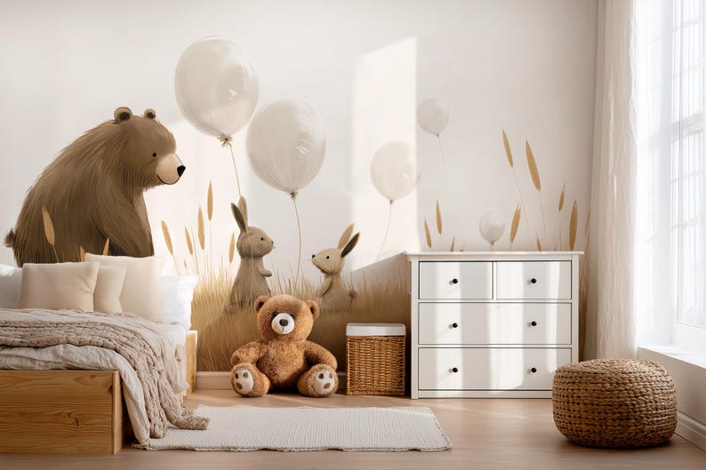 May include: A wall mural featuring a large brown bear, two rabbits, and white balloons in a grassy field. The scene includes a wooden bed with beige bedding, a brown teddy bear on the floor, a wicker basket, and a white four-drawer dresser.