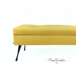 Könnte beinhalten: Eine rechteckige, gelb gepolsterte Aufbewahrungsbank mit glatter Oberfläche und festem Unterbau. Die Bank steht auf vier dünnen, angewinkelten schwarzen Metallbeinen. Der Text Rossi Furniture ist in Schwarz in der unteren Mitte abgebildet.