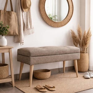 May include: A neutral-toned entryway scene featuring a tufted bench with wooden legs, a round mirror with a woven frame, and a jute rug. Accessories include a tote bag, hat, and decorative basket, creating a cozy, inviting space.