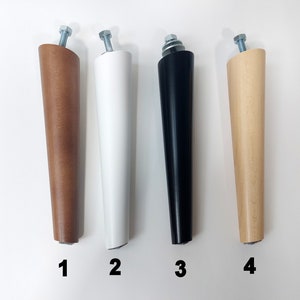Pode incluir: Quatro pernas de m&oacute;veis de madeira em diferentes cores: marrom, branco, preto e madeira natural. As pernas s&atilde;o afuniladas e t&ecirc;m um parafuso de metal na parte superior.