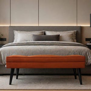 May include: A contemporary bedroom featuring a grey bed with neutral bedding and an orange bench with black legs. Two black pendant lights hang above the bed. The room has a neutral colour palette with wooden flooring and a light-coloured rug. The bed is approximately 150cm wide.