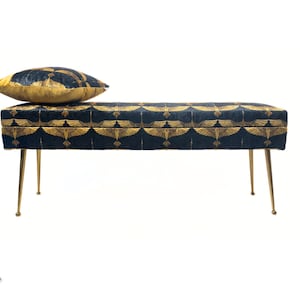 May include: A black and gold patterned bench with gold metal legs and a matching patterned pillow. The bench is a storage bench with a hinged top.