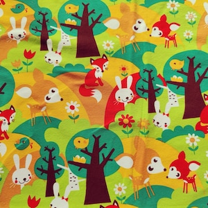 Könnte beinhalten: Ein skurriles Stoffmuster mit einer Waldszene mit Cartoon-Füchsen, Kaninchen und Rehen. Das Design umfasst Bäume, Blumen und Vögel in einer lebendigen Farbpalette aus Grün, Gelb, Orange und Rot. Geeignet für Kinderartikel.