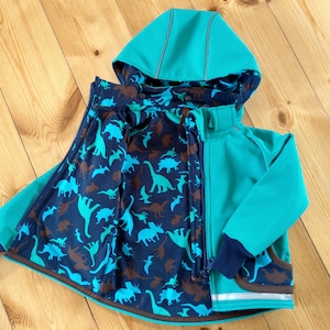 Könnte beinhalten: Eine türkisblaue Kinderjacke mit einem Dinosaurier-Musterfutter. Die Jacke hat eine Kapuze und einen Reißverschluss.