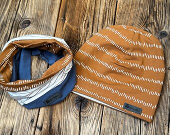May include: A brown and white striped beanie and a blue and white striped neck warmer. Both items have a small white label with the word "Mimimi" printed on them.