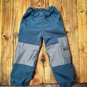 Puede incluir: Pantalón para niños azul y gris con un parche en la pierna derecha que dice "FRECH" en letras blancas.