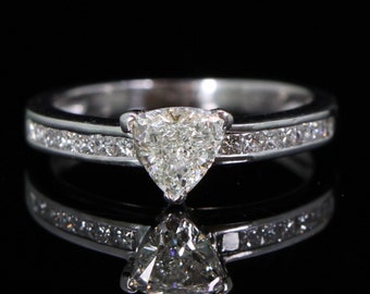 Könnte beinhalten: Ein silberner Ring mit einem dreieckigen Diamanten in der Mitte und einer Reihe kleinerer Diamanten am Rand.
