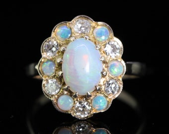 May include: A gold ring with a large white opal surrounded by smaller opals and diamonds.