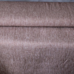 May include: A close-up of a brown fabric with a textured, woven pattern. The fabric is folded in half, showing the texture of the material.