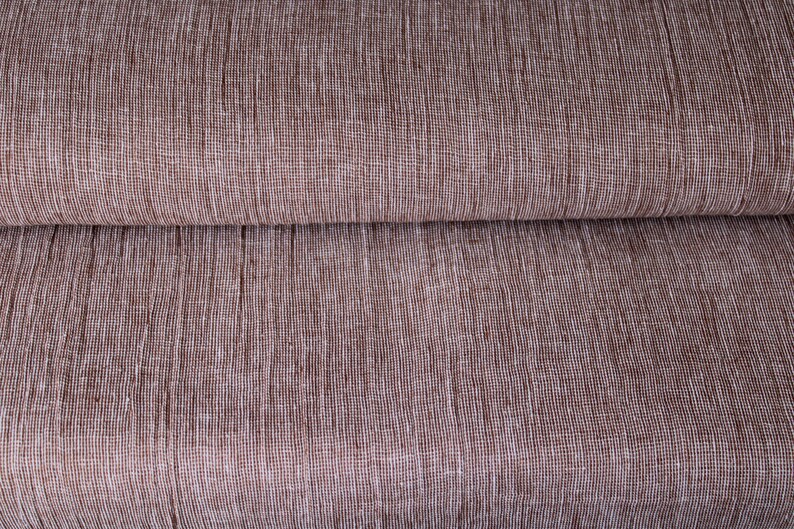 May include: Close-up of a brown fabric with a subtle white woven pattern. The fabric is folded in half, showing the texture and weave.