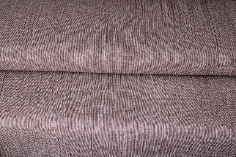 May include: Close-up of a brown fabric with a subtle woven texture. The fabric has a slightly rough, linen-like feel.
