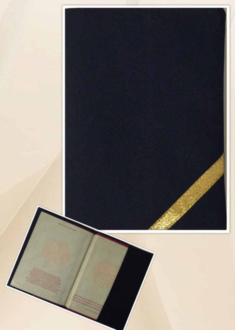 May include: A dark blue passport cover with a gold ribbon on the corner. The cover is made of a soft, textured material. The inside of the cover is lined with a red fabric. The cover is open to reveal the inside pages of a passport. The pages are printed with the German coat of arms and text in German.