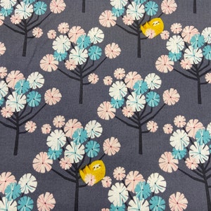 May include: Fabric with a repeating pattern of stylized trees with white, light blue, and pink flower-like blooms. The trees have dark gray trunks and branches. A yellow sloth is hanging from the branches of some of the trees. The background is a dark gray.