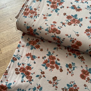 Peut inclure: Un tissu beige avec un motif floral. Les fleurs sont rouge foncé et bleu sarcelle.