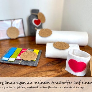 Alle Ergänzungen zu meinem Arztkoffer auf einen Blick. 5 Pflaster, Gips in 2 Größen, Verband, Wärmflasche und ein Arzt Rezept.