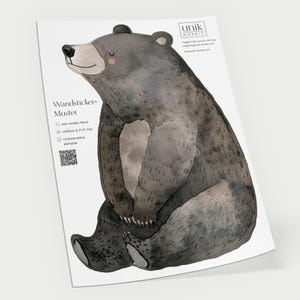 Könnte beinhalten: Aquarell-Illustration eines sitzenden Bären in Grau- und Brauntönen. Der Bär hat einen freundlichen Ausdruck und sitzt mit gekreuzten Beinen. Das Bild befindet sich auf einem weißen Hintergrund mit dem Text "Wandsticker-Muster".