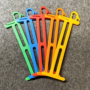May include: Six colorful plastic cable ties in green, blue, orange, and yellow. The ties are arranged in a fan shape.