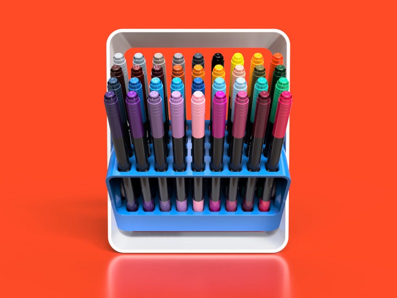 May include: A white plastic holder with a blue base containing a variety of coloured markers. The markers are arranged in rows and are all the same size.